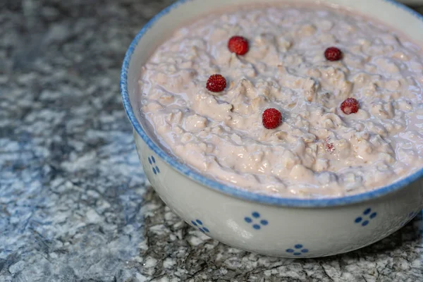 Mısır gevreği, dilimlenmiş meyve, muz, elma ve ormandaki küçük çileklerle süslenmiş taze yoğurt yakın plan. Hazır İsviçre bircher Müsli.