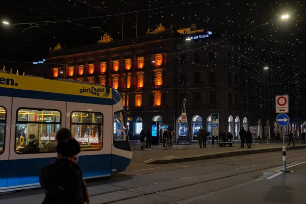 Geceleri Noel 'de Paradeplatz. Zürih 'teki bankaların ve tramvay istasyonlarının pencereleri aydınlatılmış ve Lucy adında bir sürü lamba asılmış. Zürih, 19 yaşında. Aralık 2020.