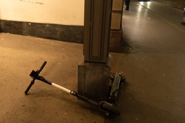 Elektrikli scooter gecenin karanlığında kaldırımda yatıyor. Paylaşım sistemi kuralları sorunu. Zürih, 19 yaşında. Aralık 2020.