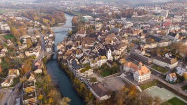 Brugg şehrinin kuzeydoğusundaki Aare nehri, yerleşim ve ticaret bölgeleri, İsviçre kantonu Aargau 'daki tarihi eski kasaba ve kumarhane köprüsü insansız hava aracı görüntüsü. Tafeljura 'nın ayaklarının üzerinde yer alan kasaba.