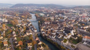 Brugg şehrinin kuzeydoğusundaki Aare nehri, yerleşim ve ticaret bölgeleri, İsviçre kantonu Aargau 'daki tarihi eski kasaba ve kumarhane köprüsü insansız hava aracı görüntüsü. Tafeljura 'nın ayaklarının üzerinde yer alan kasaba.