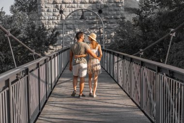 Aare Nehri 'nin asılmış köprüsünün ahşap platformunda yürüyen genç çiftin arka manzarası Eylül öğleden sonra gün batımında. Gri resim, daha doygun insanlar. Arkaplan veya duvar kağıdı konsepti için.