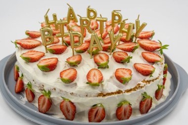 Beyaz arka planda izole edilmiş çilekli kek altın mumlarla süslenmiş doğum günü mektupları..