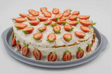 Beyaz arka plandaki izole edilmiş çilekli cheesecake taze yarım çilekle süslenmiş. Önplana odaklan.