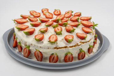 Beyaz arka plandaki izole edilmiş çilekli cheesecake taze yarım çilekle süslenmiş. Arkaplana odaklan. 