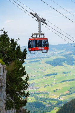 Arka planda dağ manzaralı kırmızı bir teleferik yükseliyor. Seyahat ve doğa fotoğrafçılığı. Appenzell, İsviçre - 05.08.2022