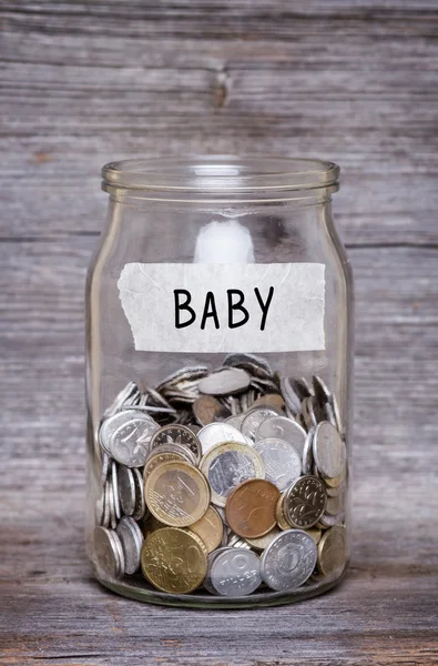 Baby, money jar with coins on wood table — Stock Photo, Image