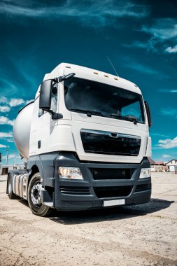 Karavanlı bir kamyon, yanıcı sıvılı bir tank, güneşli bir gün dışarıda, metalik renk kabı, beyaz bulutlu mavi gökyüzü, çakıl