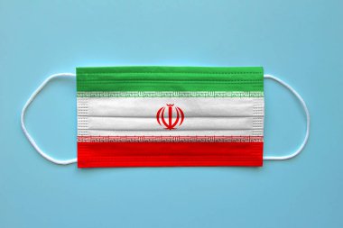 Temiz bir arkaplanda İran bayrağı olan bir yüz maskesi. Kavram: Salgın sırasında İran.