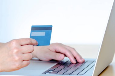Kredi kartı ve dizüstü bilgisayarla online alışveriş yapan bir kişi..