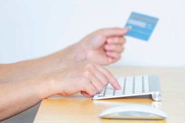 Kredi kartı ve bilgisayarla online alışveriş yapan bir kişi.