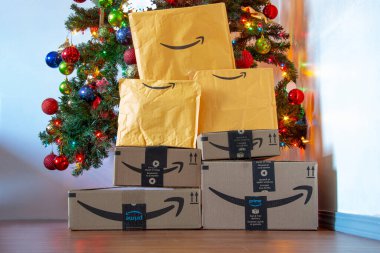 Calgary, Alberta, Kanada. 16 Kasım 2020. Noel ağacının altında süsleri ve ışıkları açık olan Amazon kutuları ve zarfları. Konsept: Tatil döneminde paket teslimatı.