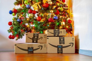 Calgary, Alberta, Kanada. 16 Kasım 2020. Süs ve ışıkların açık olduğu bir Noel ağacının altındaki Amazon kutuları. Konsept: Tatillerde alışveriş.