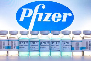Calgary, Alberta, Kanada. 23 Kasım 2020. Covid-19 aşı şişeleri arka planda Pfizer logosu olan şişeler.