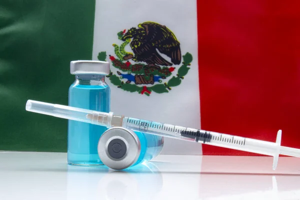 Vaccine on a vial bottle and injection Syringe with a Mexican flag on the background