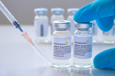Calgary, Alberta, Kanada. Ocak 03, 2021. Elinde AstraZeneca Covid-19 aşı şişesi olan bir hemşire temiz bir arkaplanda enjeksiyon şırıngası taşıyor..