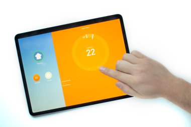 iPad Pro kullanan bir kişi yuvanın akıllı termostat uygulamasını kullanarak ısıyı açar.