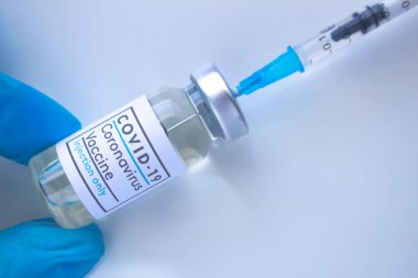 Covid-19 aşısı olan bir sağlık çalışanı ve beyaz arka planda bir şırınga.