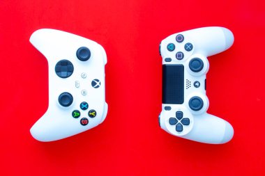Calgary, Alberta. Kanada mı? 3 Şubat 2021. Kırmızı arkaplanda Playstation 'a bakan bir Xbox kumandası.