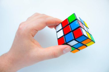 Calgary, Alberta, Kanada. 15 Mart 2021. Rubik küp tutan bir insan. Beyaz arka planda 3x3 Rubik küp. Zor görevler.