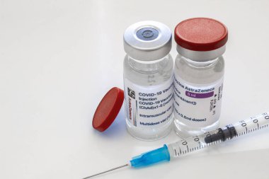 Calgary, Alberta, Kanada. 17 Nisan 2021. Bir çift AstraZeneca Covid-19 aşı şişeleri ve temiz bir masaya şırınga..