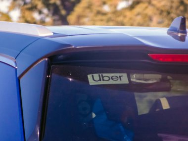 Calgary, Alberta, Kanada. 17 Ekim 2025. Bir arabanın arka camında, modern sürüş paylaşımını, şehir hareketliliğini ve kolaylığı temsil eden bir Uber çıkartması görünür bir şekilde sergilenmektedir..
