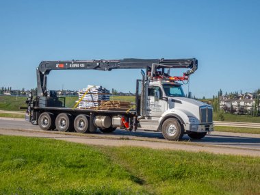 Calgary, Alberta, Kanada. 17 Ekim 2025. Bir vinç kamyon taşımacılığı otoyolda malzeme üretiyor, inşaat lojistiği, ağır sanayi ve altyapı gelişimini simgeliyor.