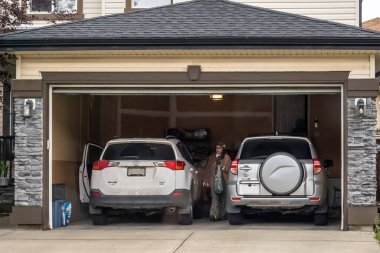 Calgary, Alberta, Kanada. 28 Ekim 2025. İki SUV, biri beyaz, biri gümüş, açık bir garajın içine park edilmiş..
