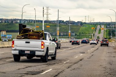 Calgary, Alberta, Kanada. 28 Ekim 2025. Beyaz bir kamyonet, bir Toyota Tundra, yatağında mobilya ve halı taşıyor, başka bir trafikle otoyolda gidiyor..