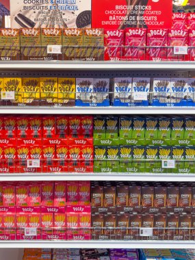 Calgary, Alberta, Kanada. 28 Ekim 2025. Popüler Japon Çopur ve Pejoy bisküvilerinin çeşitli aromalarıyla dolu bir perakende rafı, canlı paketler sergiliyor..