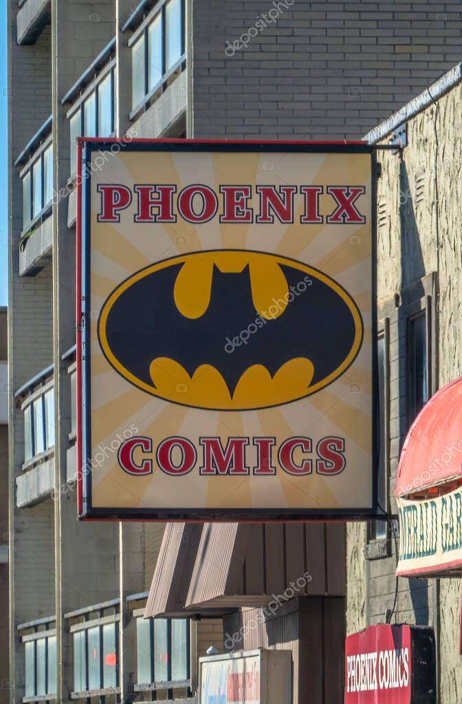 Calgary, Alberta, Canada. Oct 28, 2025. The Phoenix Comics storefront sign, prominently featuring the iconic Batman logo, hanging on an urban building.