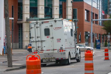 Calgary, Alberta, Kanada. 1 Kasım 2025. Turuncu trafik varilleri ve görünür ekipman kompartımanları olan kentsel bir inşaat alanında çalışan ENMAX hizmet kamyonu