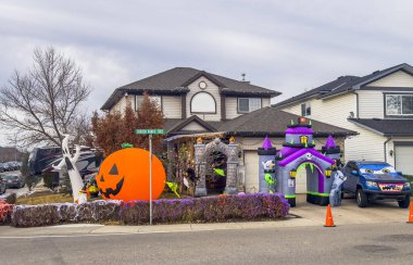 Calgary, Alberta, Kanada. 2 numara, 2025. Büyük şişme balkabağı, mor ve yeşil lanetli kale, bir sokak köşesinde iskeletler ve koniler