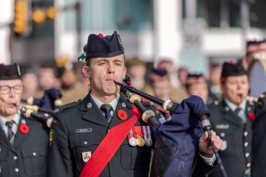 Calgary, Alberta, Kanada. 11 numara, 2025. Askeri üniformalı gaydacı, madalyalı, kırmızı kuşaklı ve haşhaş bir anma gününde şehir merkezinde gösteri yapıyor..