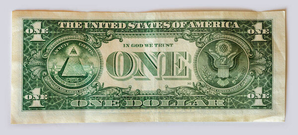 Обратный ход однодолларовой купюры США, изображающей пирамиду Великой Печати с глазом, В БОГЕ мы ДОВЕРЯЕМ и орла со щитом и стрелами.