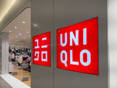 Calgary, Alberta, Kanada. 22 Kasım 2025. Parlak, kırmızı ışıklı UNIQLO logosu ve bir alışveriş merkezindeki giyim perakendecisinin mağazasının açık girişi..