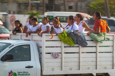 Huatulco, Oaxaca, Meksika. Aralık 18, 2025. Beyaz dantel elbiseli bir grup kız ve kadın Meksika 'daki yerel bir festivalde Santa Maria Huatulco kamyonunun arkasında geziyorlar..