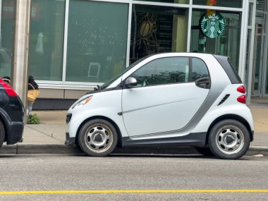 Calgary, Alberta, Kanada. 2 Ocak 2025. White Smart Fortwo Compact Araba Starbucks Kahve Dükkanı 'nın önündeki bir caddede park edilmiş.