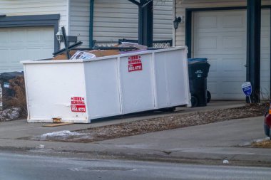 Calgary, Alberta, Kanada. 22 Ocak 2026. Banliyödeki bir konutun önünde içi enkaz dolu beyaz bir çöp tenekesi duruyor..