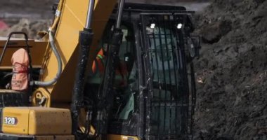 Calgary, Alberta, Kanada. 4 Mart 2026. Bir inşaat işçisi kış mevsiminde çamurlu bir inşaat alanında sarı bir tırtıl 320 kazıcı kullanıyor..