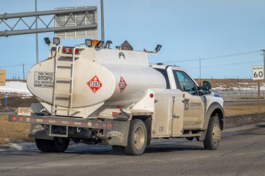 Calgary, Alberta, Kanada. 8 Mart 2026. Beyaz bir Cooper Malzeme Kiralama, geniş bir tank ve tehlikeli malzeme pankartlarıyla bir otoyolda ilerliyor..
