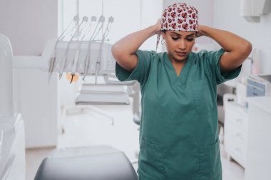 Beyaz lateks eldivenli Afro-Amerikalı dişçi dişçiye odaklanırken genç sarışın beyaz kadın ağzını açıyor.