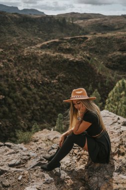 Şapkalı genç bir kadın kameraya bakıyor.