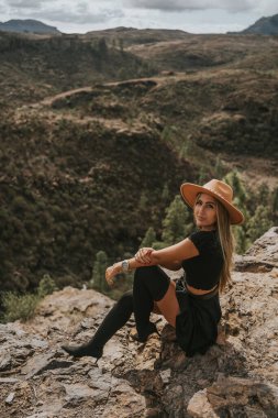 Şapkalı genç bir kadın kameraya bakıyor.