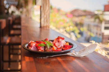 Çiçekli ağaçlar ve güneşli binaları olan caddeye bakan bir restoranın barında üzüm, çilek ve dondurma ile taze ve lezzetli bir tatlı..