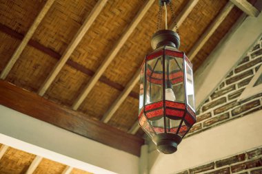 Modern bir tavan arasından sarkan kırmızı ve şeffaf camlı güzel bir klasik fener.