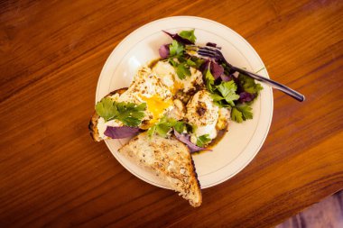 Lezzetli bir sabah kahvaltısı haşlanmış yumurta Benedict, salata, peynir ve ahşap bir masada kızarmış ekmek..