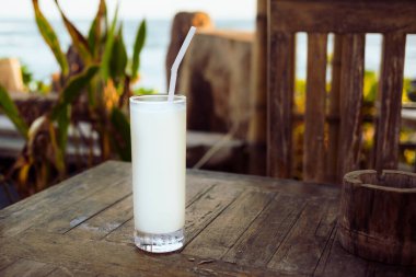 Akşam ışığında, plaj barındaki ahşap bir masada parlayan limon suyu. Sıcak bir günde ferahlatıcı.
