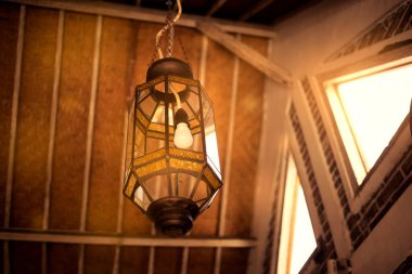 Altın güneş ışığı altında, eski bir karanlık tavan arasında elektrik ampulü ile güzel bir klasik fener..