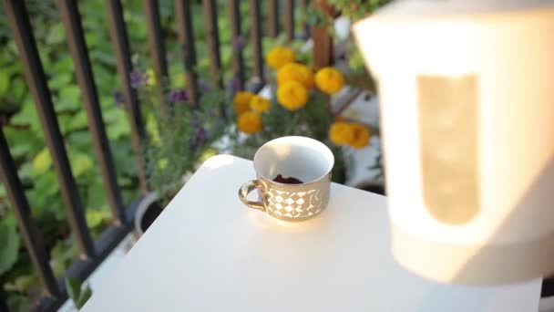 Eine Frau kocht heißen Kaffee im Balkongarten — Stockvideo